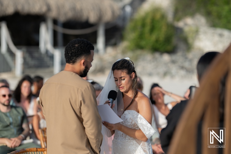 A Beach Wedding Ceremony in a Tropical Setting Where a Couple Exchanges Vows Surrounded by Guests During Sunset on a Warm Evening