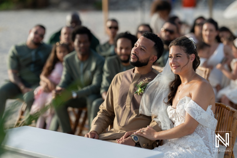 A Beautiful Beach Wedding Celebration Featuring a Couple Smiling at Their Guests During an Outdoor Ceremony at Sunset Surrounded by Loved Ones