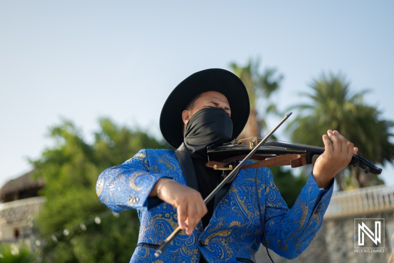 A Musician Performing With a Violin Against a Tropical Backdrop During a Vibrant Outdoor Event at Sunset