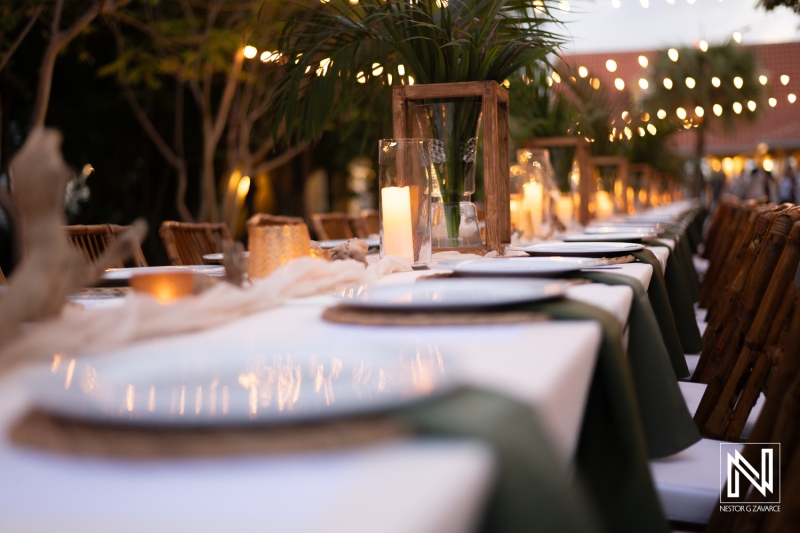 Elegant Outdoor Dining Setup Featuring Long Tables Adorned With Greenery and Soft Lighting, Creating a Warm Atmosphere for an Evening Gathering