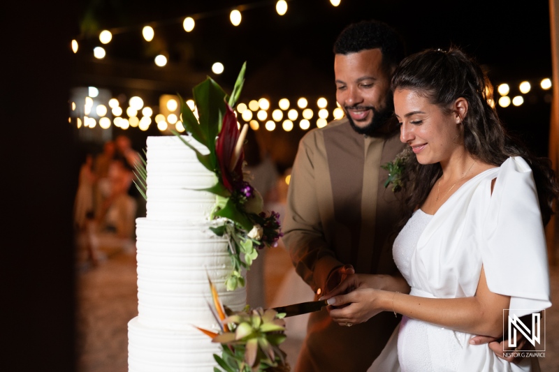 Couple Cutting a Wedding Cake Together at a Beautifully Decorated Outdoor Reception Under String Lights in the Evening