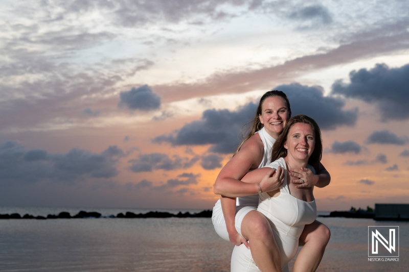 Joyful LGBT wedding celebration at sunset in Willemstad, Curacao featuring two brides embracing love and happiness
