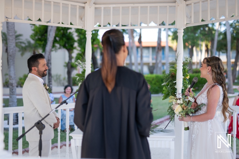 A beautiful wedding ceremony under a gazebo in a lush garden with an emotional bride and groom exchanging vows at sunset