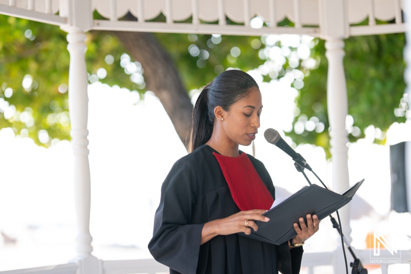 A confident speaker presenting at an outdoor event in a park, delivering a speech while dressed in formal attire and holding a folder under the bright sunlight