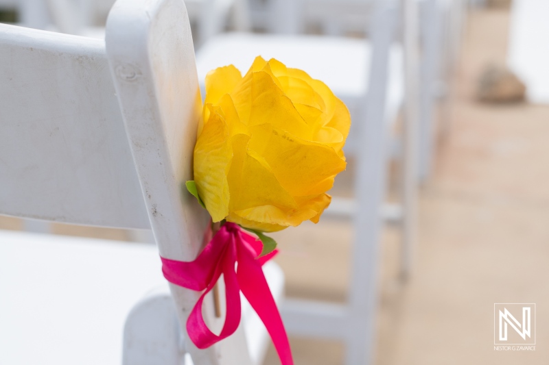 Beautiful floral decoration enhances the elegant wedding ceremony at Fort Beekenburg in Curacao, featuring vibrant yellow roses and bright pink ribbons
