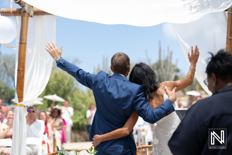 Couple celebrates wedding ceremony at scenic Fort Beekenburg in Curacao surrounded by guests under sunny skies