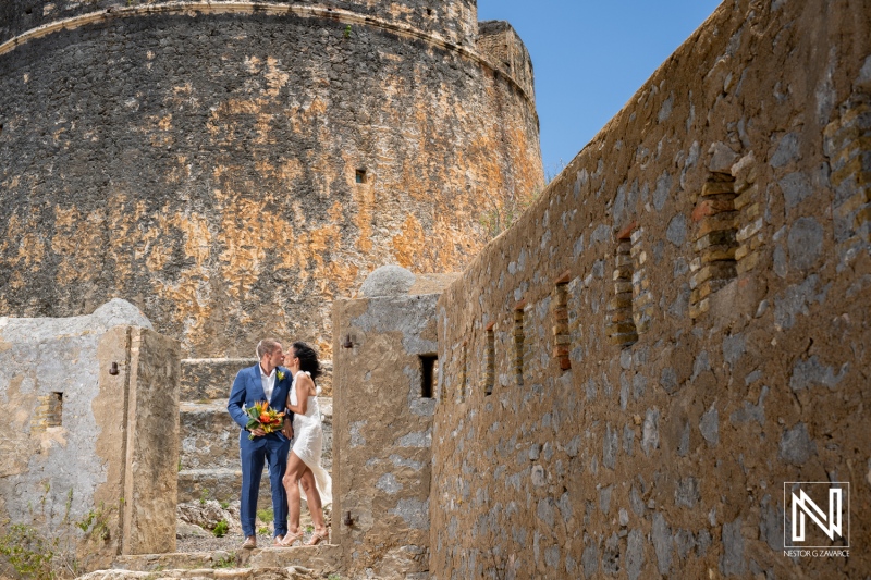 Wedding celebration at Fort Beekenburg in Curacao featuring a couple sharing a tender moment surrounded by historic stone walls