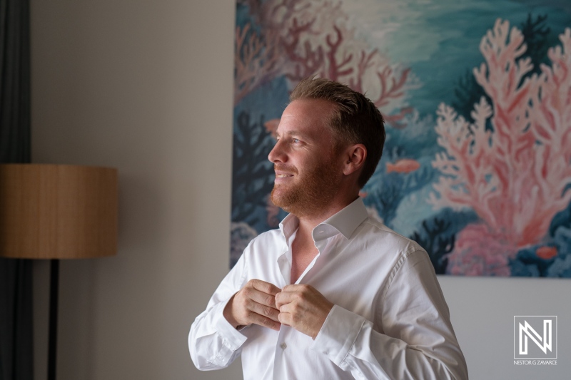 Groom getting ready in Curacao for a wedding celebration amid vibrant coral-themed decor