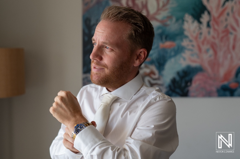 Groom preparing for wedding in Curacao with vibrant coral-themed backdrop