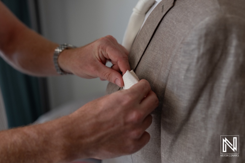 Wedding preparations unfold in Curacao as groom's suit is expertly adjusted with care and attention to detail