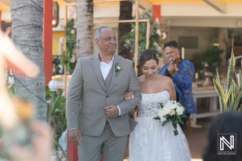 Emotional wedding moment in Curacao with bride and father walking down the aisle surrounded by tropical decor