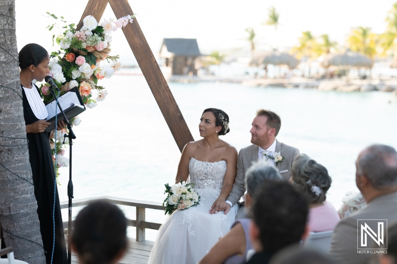 Wedding ceremony in Curacao featuring a beautiful couple and heartfelt vows by the water with family and friends gathered in the background