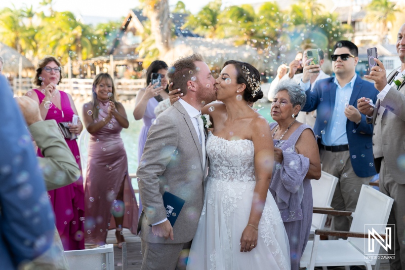 Beautiful wedding celebration in Curacao with joyful guests, bubbles, and a loving couple kissing on their special day