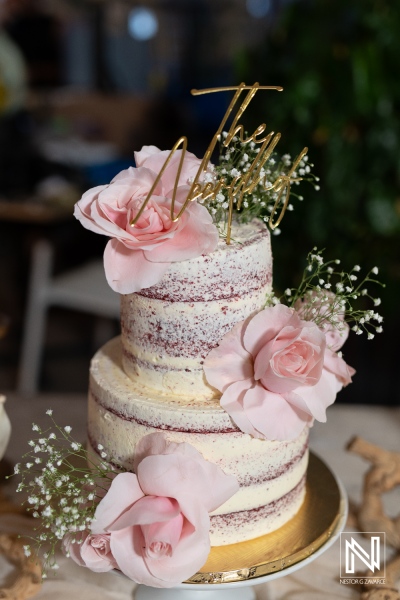 Elegant wedding cake adorned with pink flowers and delicate greenery in Curacao's stunning setting