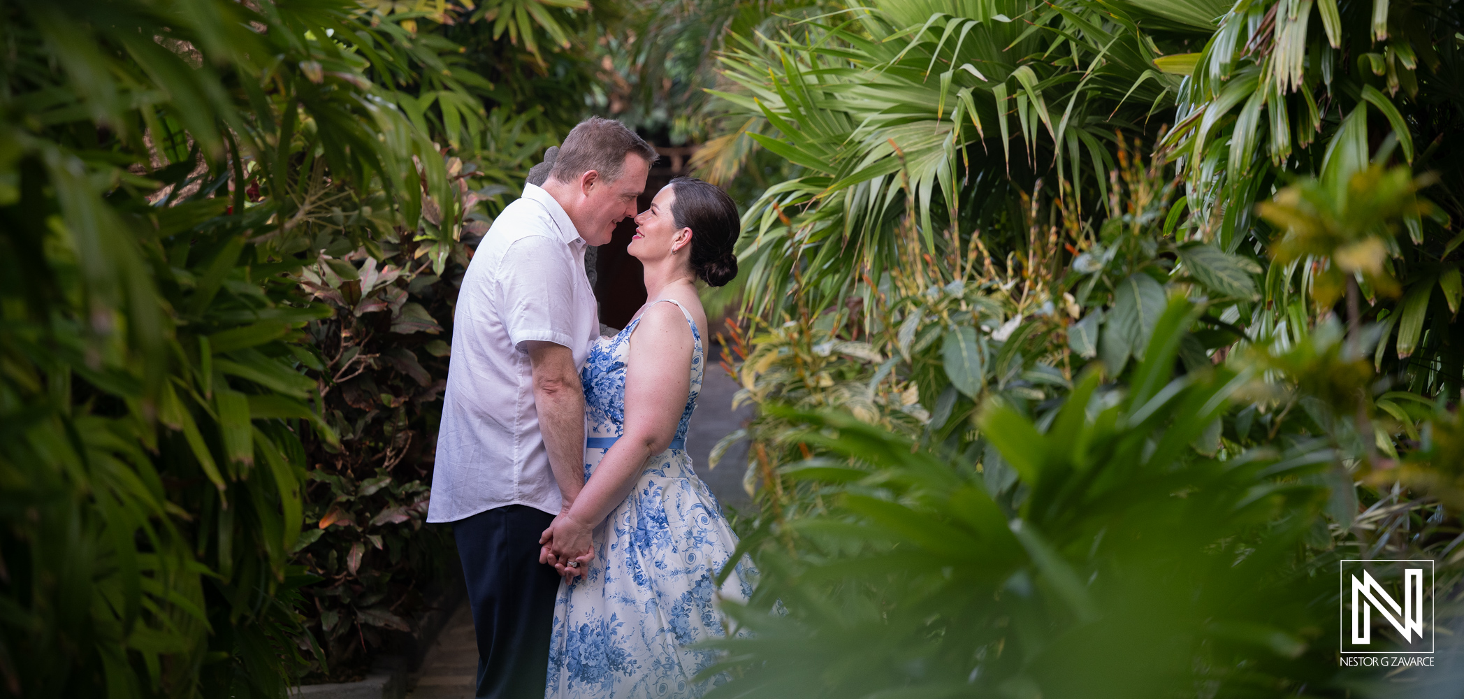 Nicole and Zachary share a tender moment framed by lush green foliage at Baoase Luxury Resort during their Curacao vow renewal.